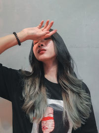 Portrait of young woman standing against wall