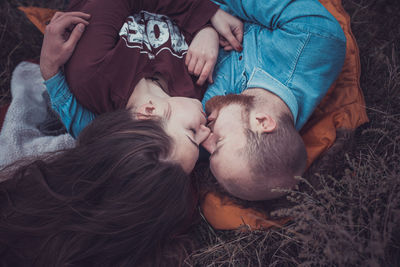 High angle view of couple kissing lying on grass outdoors