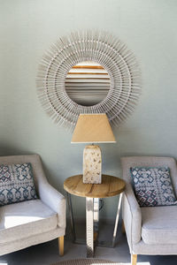 Electric lamp on table amidst chair in hotel room