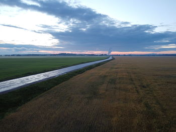 Empty road amidst field against sky