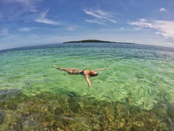Woman wearing bikini swimming in sea against sky