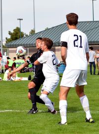 Full length of boys playing soccer on grass