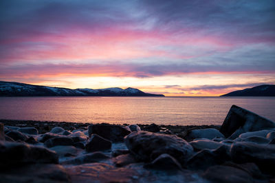 Rocks on beach against sky during sunset