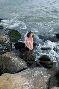 Rear view of man standing on rock by sea