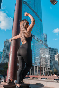 Woman with arms raised against modern buildings in city