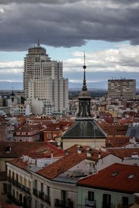 Buildings in city against cloudy sky