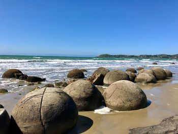 Rocks on beach against clear blue sky