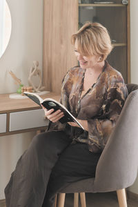 Young woman using phone while sitting on sofa at home