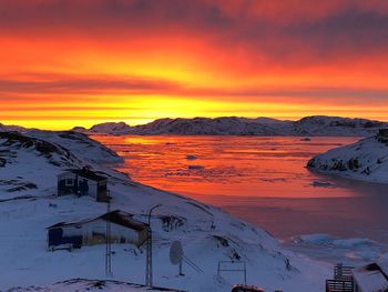 Scenic view of snow covered mountains against orange sky