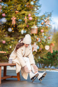 Woman sitting on seat in park during winter