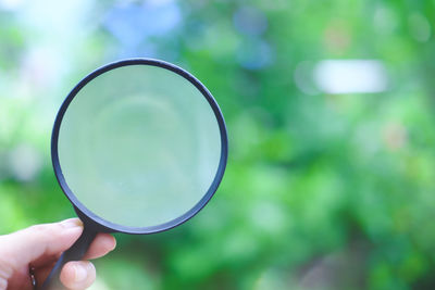 Close-up of hand holding magnifying glass outdoors