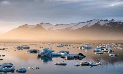 Scenic view of ocean and ice against sky during sunset