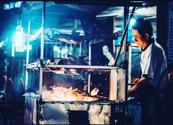 Side view of chef grilling meat at food stall