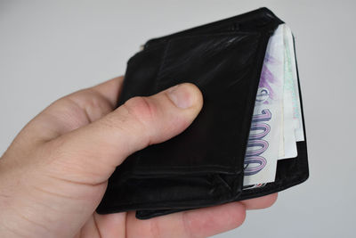 Close-up of hand holding paper over white background