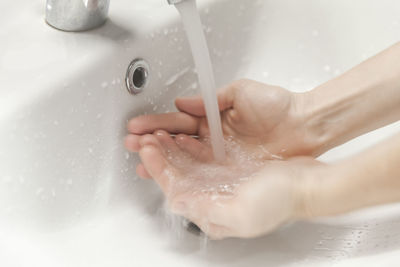 Close-up of person washing hands in sink