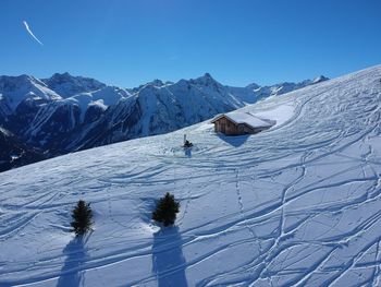 Scenic view of snow covered mountains against blue sky