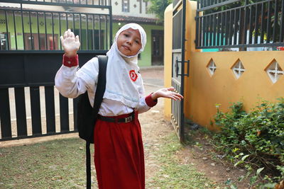 Portrait of girl in hijab standing against gate