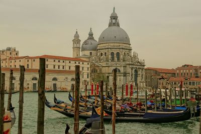 Santa maria della salute by grand canal with gondolas against sky in city