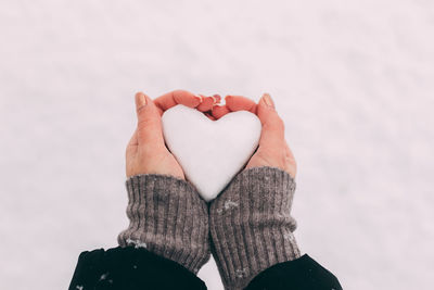 Close-up of woman holding heart shape in winter