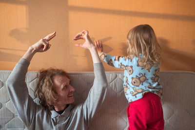 Mature man with granddaughter on sofa in living room at home