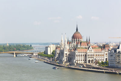 Buildings by river in city against sky