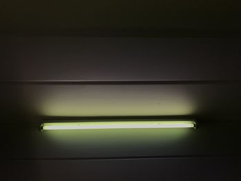 Low angle view of illuminated electric lamp on wall