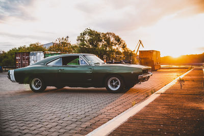 Car parked on road against sky at sunset