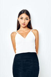 Portrait of young woman standing against white background