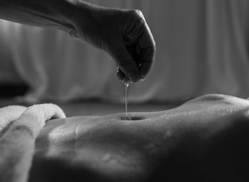Close-up of hand pouring oil before massage