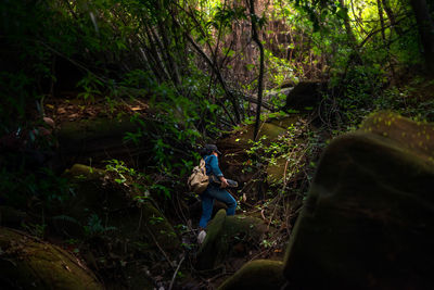 Man climbing on rock in forest