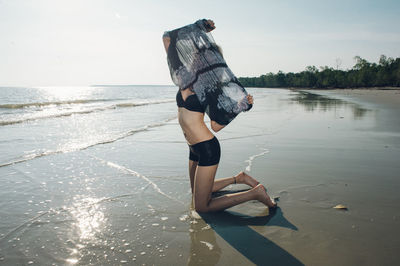 Portrait of woman with scarf on beach against sky