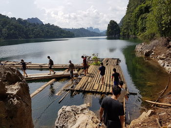 People walking on wooden raft over lake