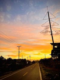 Silhouette electricity pylons against sky during sunset