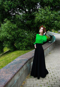 Portrait of woman wearing wreath while standing against tree