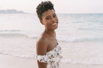 Portrait of smiling young woman standing on beach