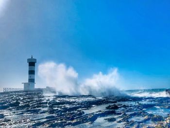 Lighthouse by sea against sky