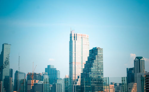 Modern buildings in city against clear blue sky