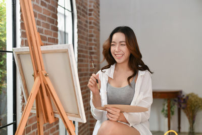 Smiling woman painting in home