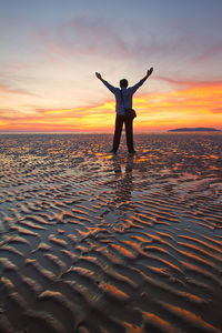 Silhouette man standing on beach against sky during sunset