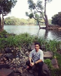 Portrait of man sitting on mobile phone in lake