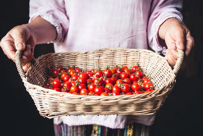 Close-up of hands holding cherry tomatoes in basket