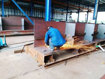 Rear view of welder welding metal at factory
