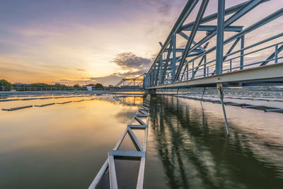 Bridge over river against sky during sunset