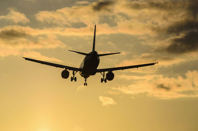 Low angle view of silhouette airplane against sky during sunset