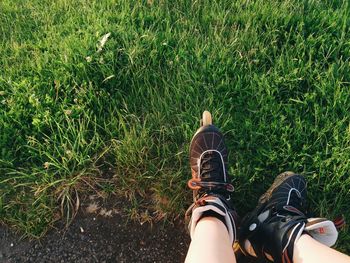 Low section of person wearing roller skates on grassy field