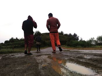 Rear view of people with dog on shore against sky