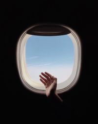 Cropped hand gesturing against airplane window