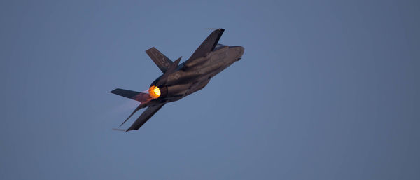 Low angle view of airplane flying against clear blue sky