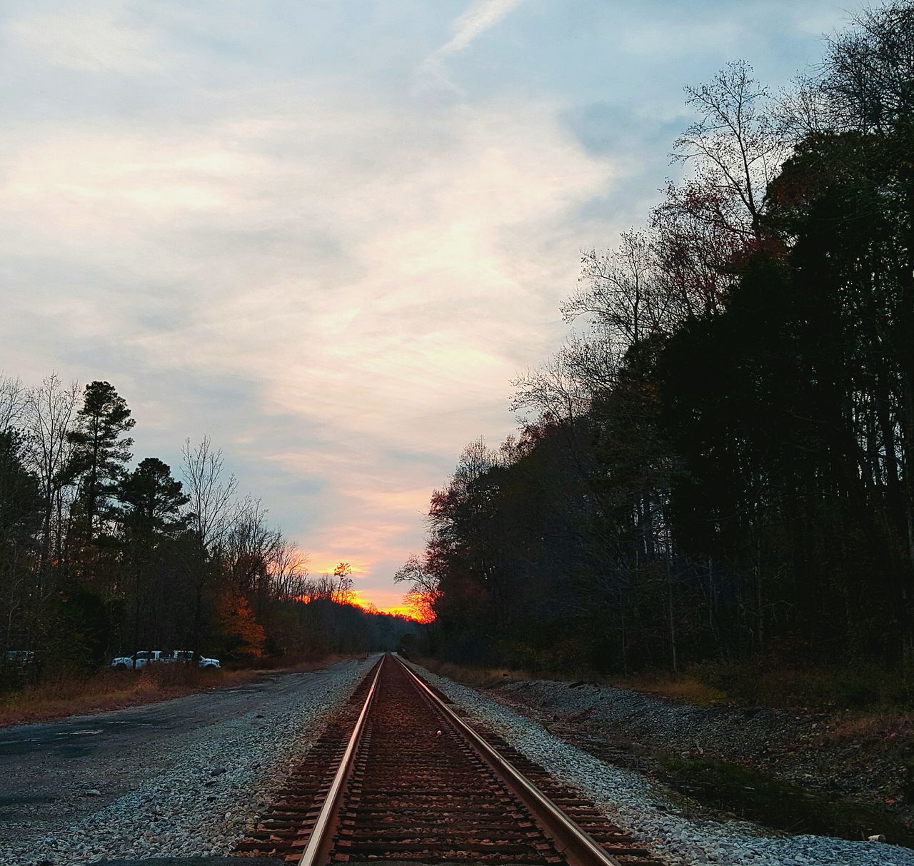 the way forward, transportation, railroad track, diminishing perspective, tree, vanishing point, sky, rail transportation, road, cloud - sky, bare tree, sunset, no people, long, nature, road marking, straight, surface level, outdoors, railway track