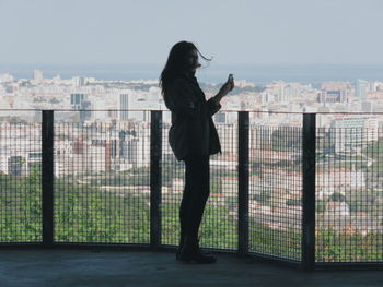 Side view of woman standing against buildings in city